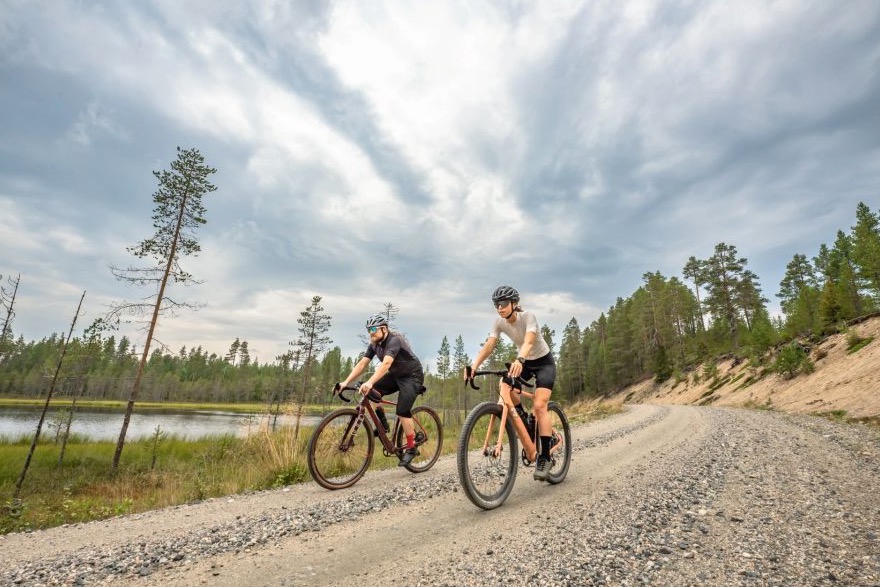 Gravel cyclists exploring a quiet northern road in Ruka-Kuusamo
